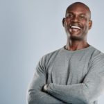 A man with his arms crossed smiling for the camera.